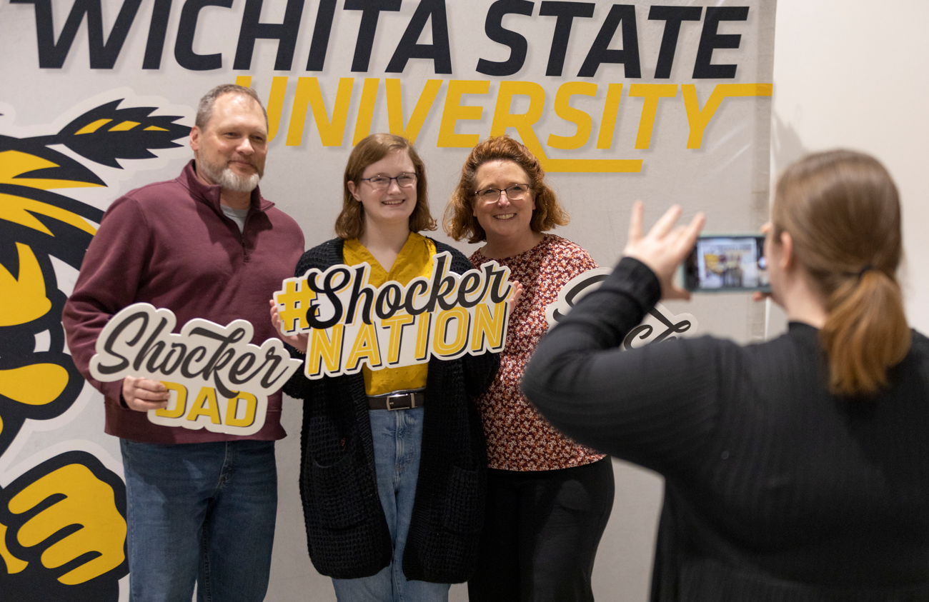 Admitted student and parents smile taking a picture