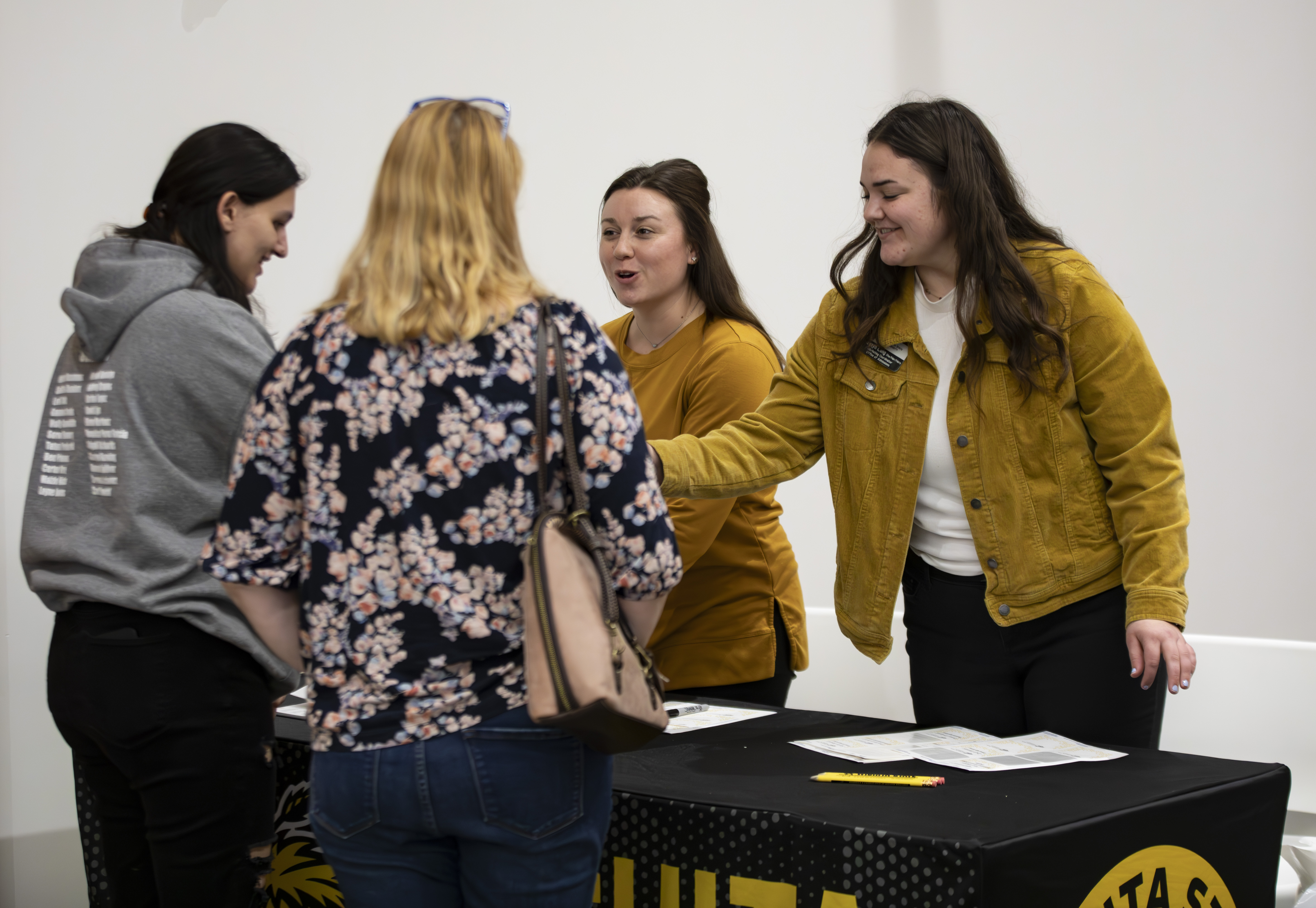 Admissions staff smiling and handing publications to a student