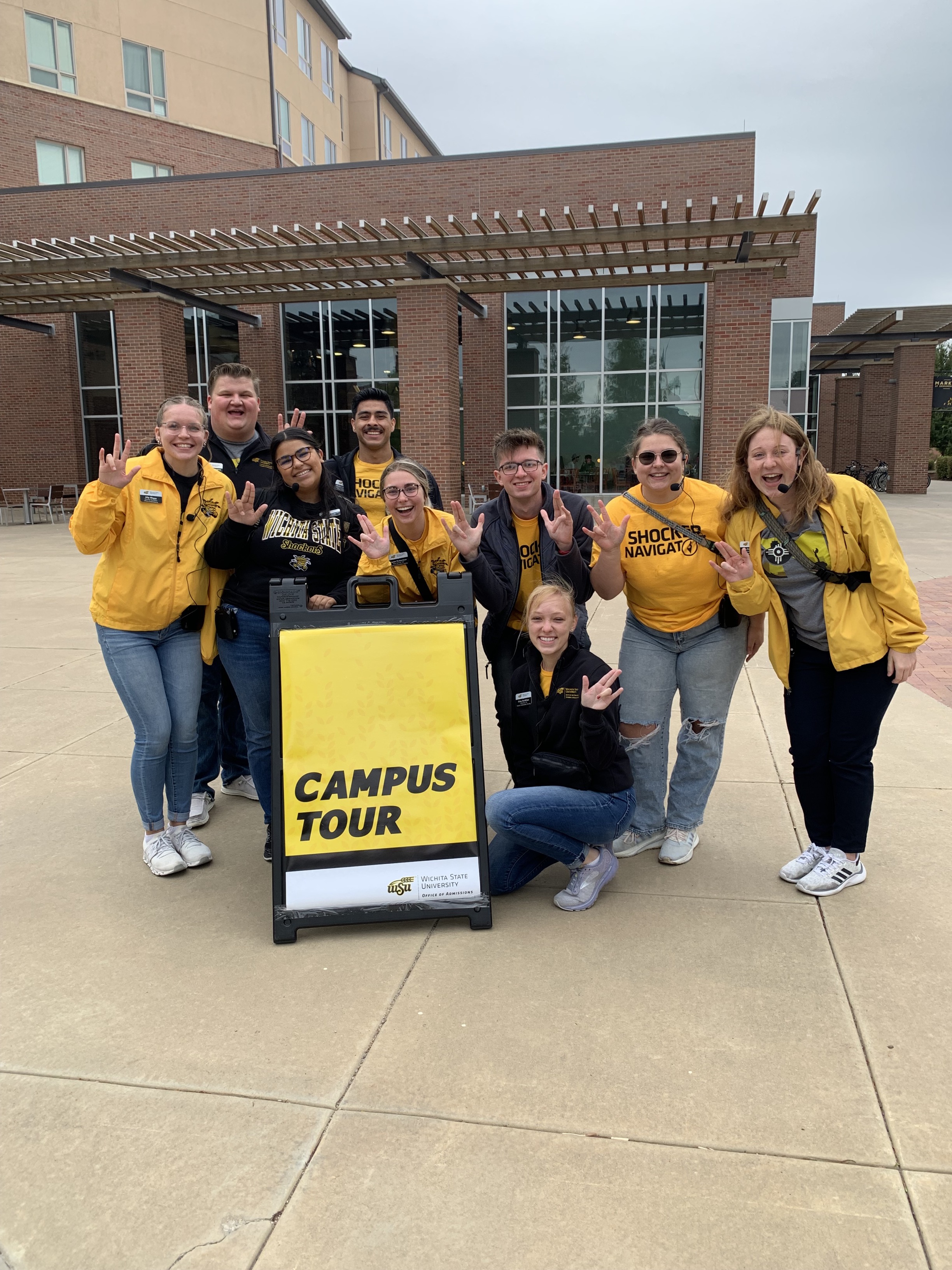 Tour guides gathered around a Campus Tour sign 