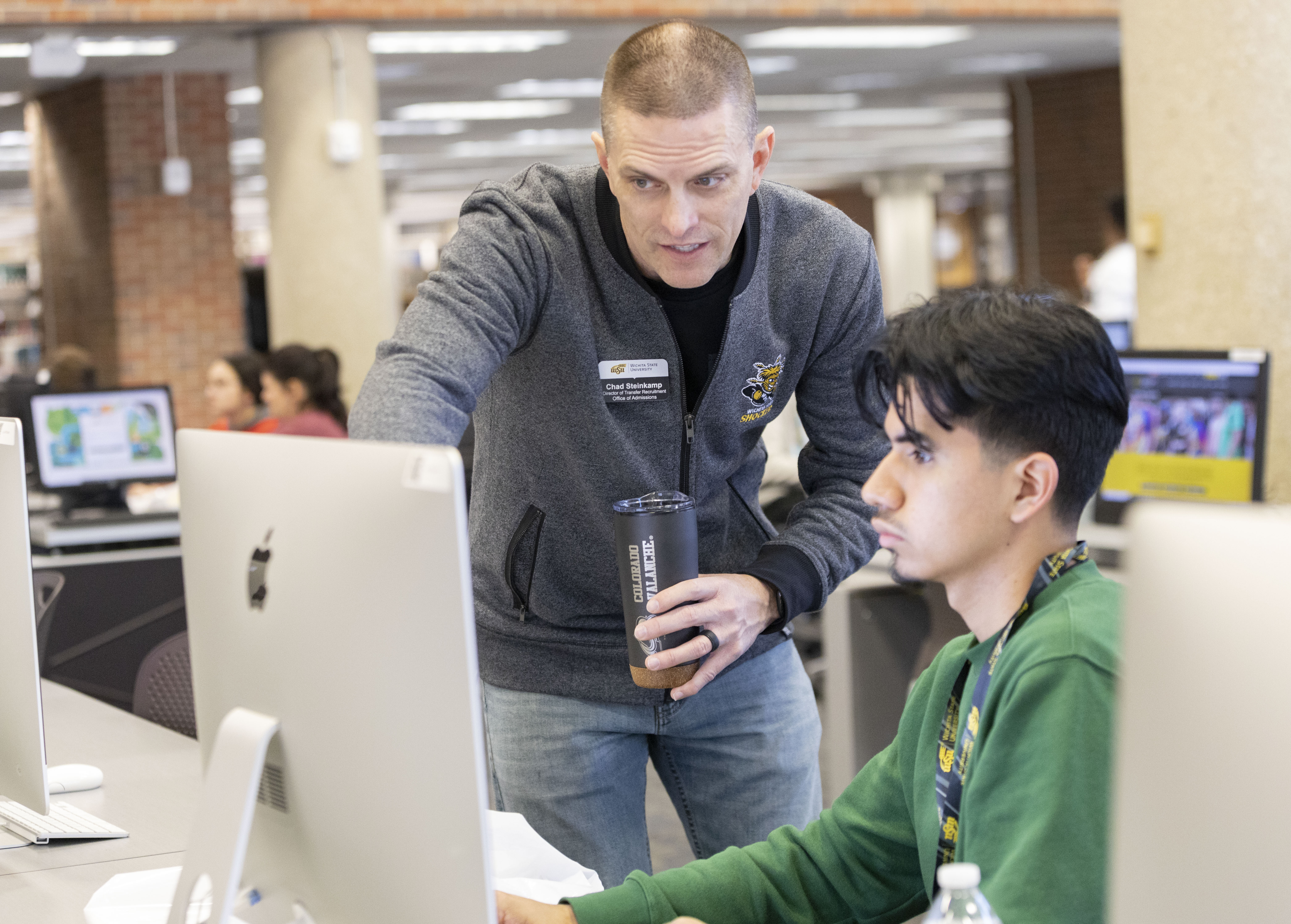 Admissions staff helping a student at a computer